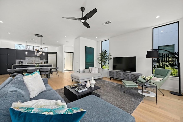 living room with visible vents, baseboards, ceiling fan, recessed lighting, and light wood-style floors