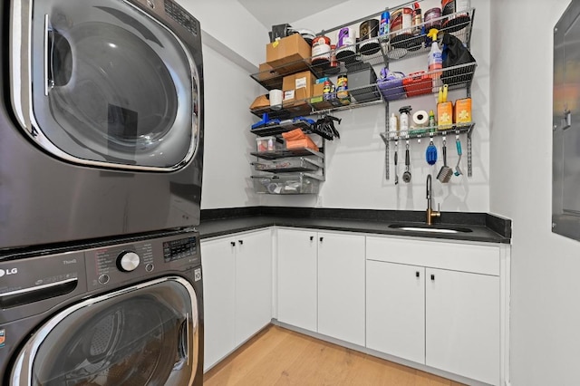 washroom featuring stacked washer and dryer, indoor wet bar, light wood-style floors, cabinet space, and a sink