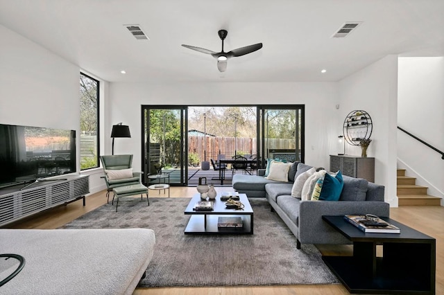 living room featuring a wealth of natural light, visible vents, and stairs