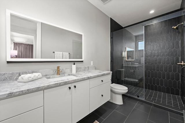 full bath with tile patterned flooring, toilet, vanity, and tiled shower