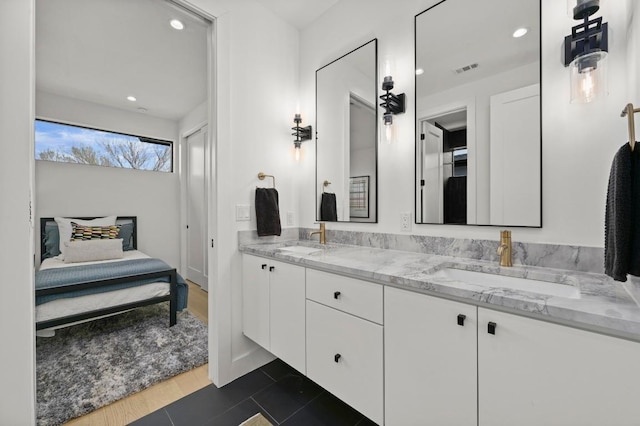 ensuite bathroom featuring double vanity, visible vents, ensuite bathroom, and a sink