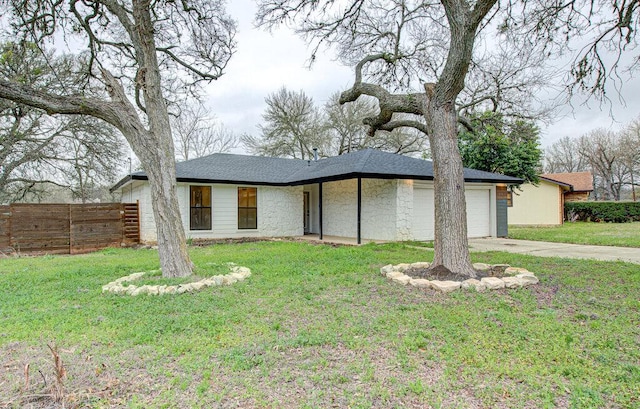 view of front of home featuring driveway, fence, a front yard, a shingled roof, and a garage