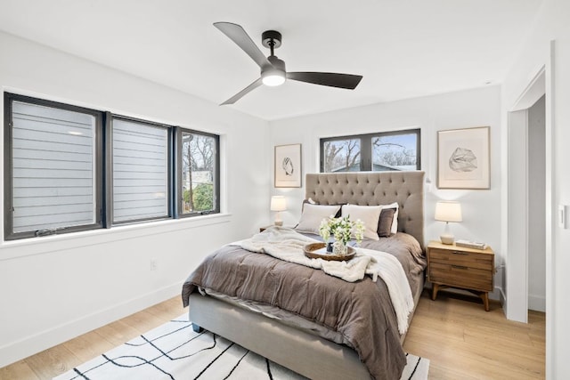 bedroom with light wood-type flooring, baseboards, and a ceiling fan