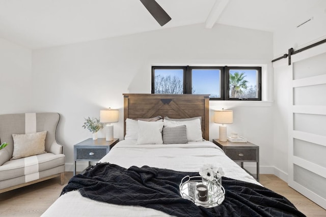 bedroom featuring light wood finished floors, vaulted ceiling with beams, baseboards, ceiling fan, and a barn door