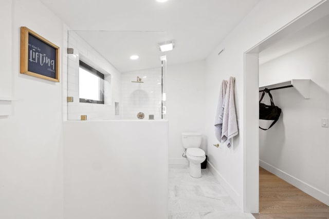 bathroom with baseboards, toilet, and a walk in shower