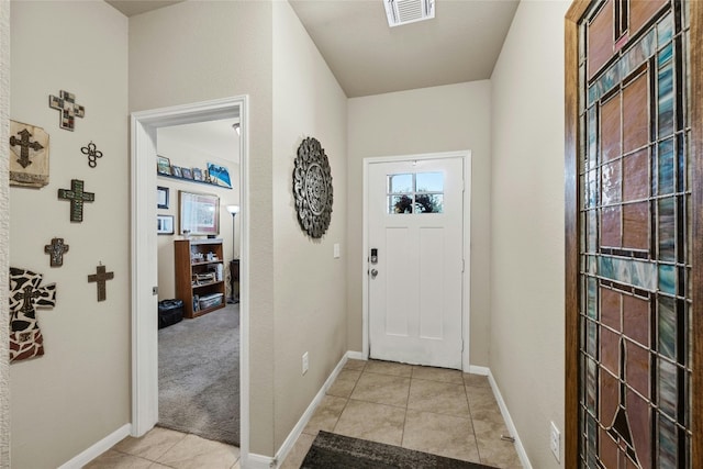 entryway with light tile patterned floors, visible vents, baseboards, and light colored carpet