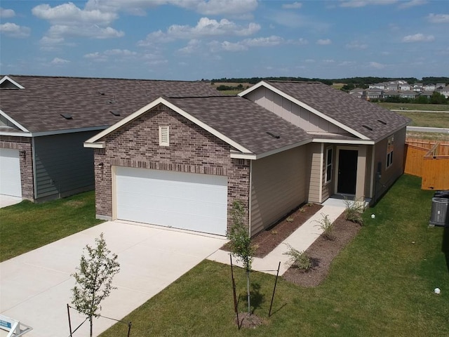 view of front of property with a front lawn, concrete driveway, an attached garage, a shingled roof, and brick siding