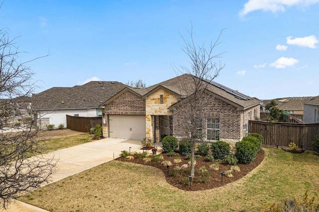 view of front of property featuring brick siding, a front lawn, fence, roof mounted solar panels, and driveway