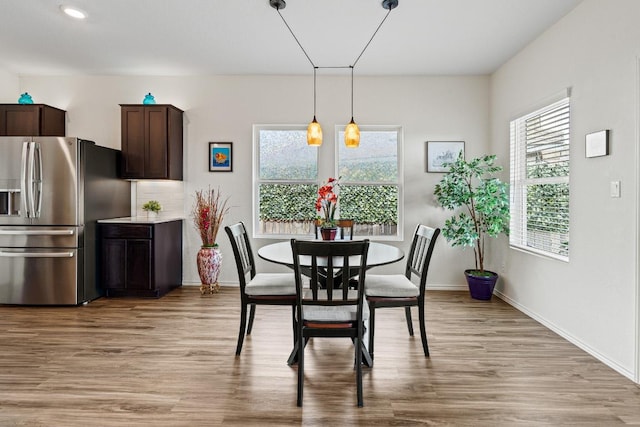 dining space with baseboards and light wood finished floors