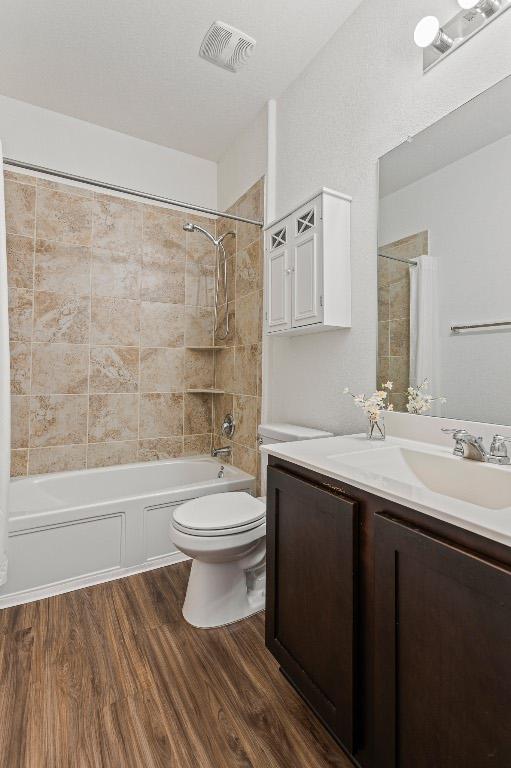 full bath featuring visible vents, toilet, wood finished floors, tub / shower combination, and vanity