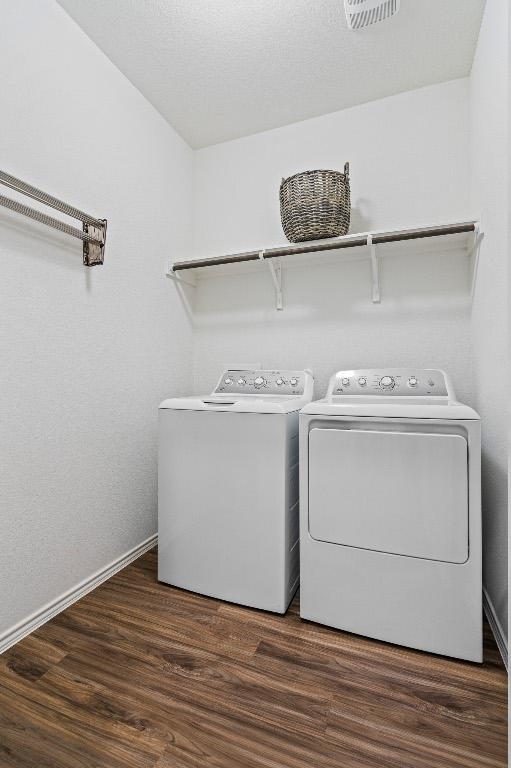 clothes washing area featuring wood finished floors, visible vents, baseboards, laundry area, and separate washer and dryer