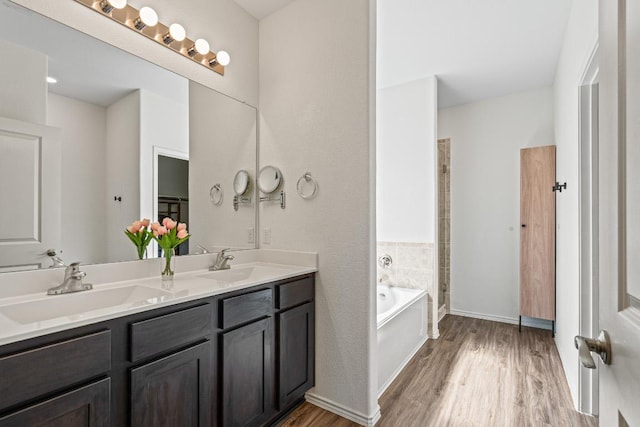 701 Mallow Rd, Leander, TX 78641 - full bathroom featuring wood finished floors, double vanity, a garden tub, a shower, and baseboards