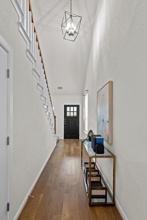 entryway with baseboards, high vaulted ceiling, stairs, and hardwood / wood-style flooring