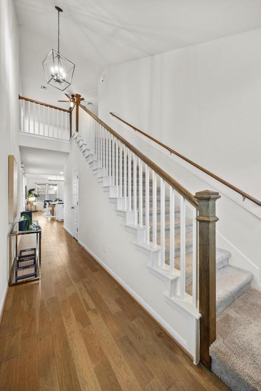 stairway featuring ceiling fan, baseboards, hardwood / wood-style floors, and a towering ceiling