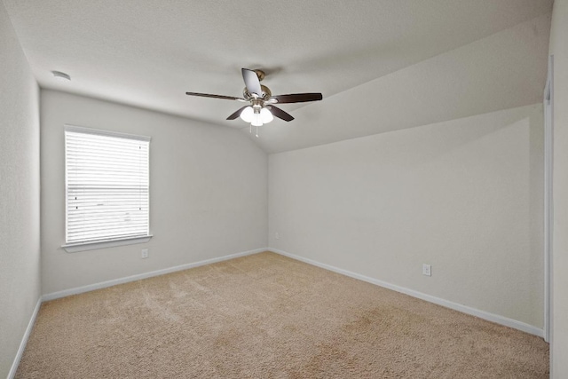 spare room featuring vaulted ceiling, carpet, baseboards, and ceiling fan