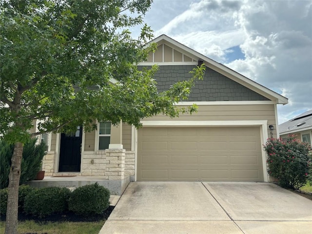 craftsman-style home featuring stone siding, an attached garage, and concrete driveway