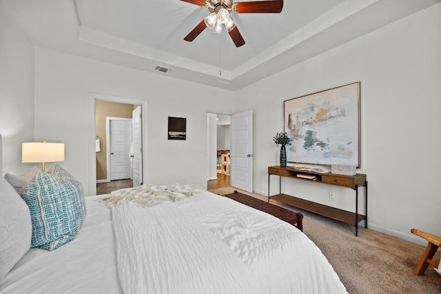 bedroom featuring visible vents, baseboards, carpet flooring, a raised ceiling, and a ceiling fan