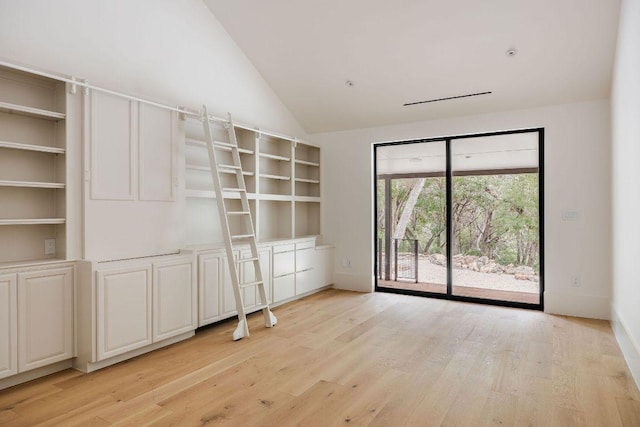 spare room with vaulted ceiling, baseboards, and light wood-type flooring