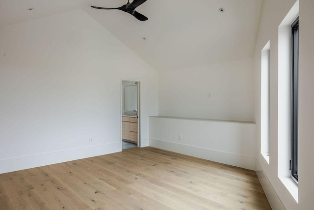 spare room with baseboards, high vaulted ceiling, wood finished floors, and a ceiling fan