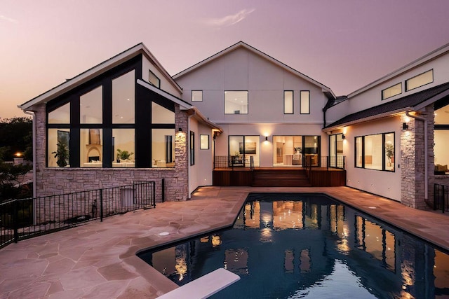 back of property featuring stucco siding, a patio area, a fenced in pool, and a wooden deck