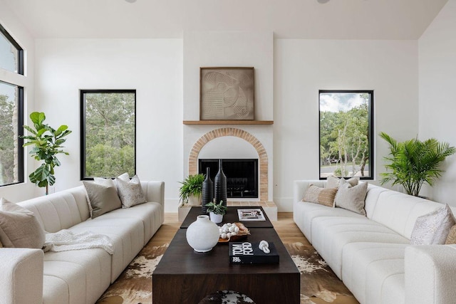 living room with plenty of natural light, wood finished floors, and a fireplace with raised hearth