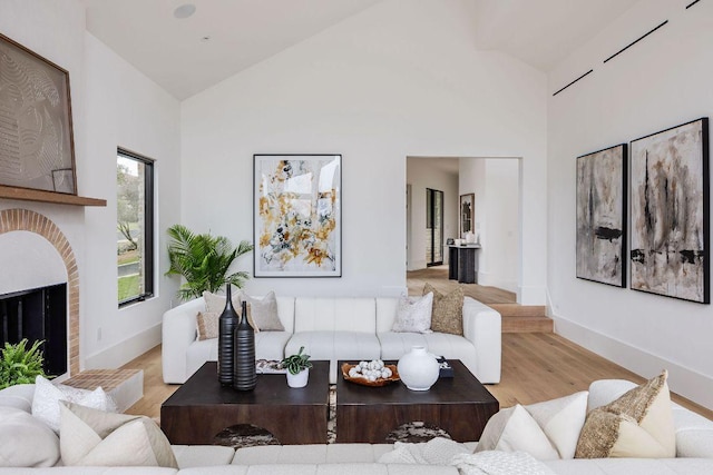 living room with baseboards, a fireplace, light wood-type flooring, and high vaulted ceiling