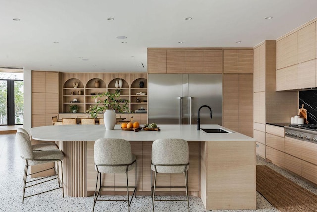 kitchen with a sink, a kitchen breakfast bar, light speckled floor, modern cabinets, and built in fridge