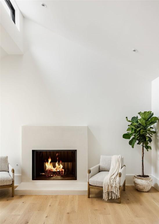 living area featuring a warm lit fireplace and wood finished floors