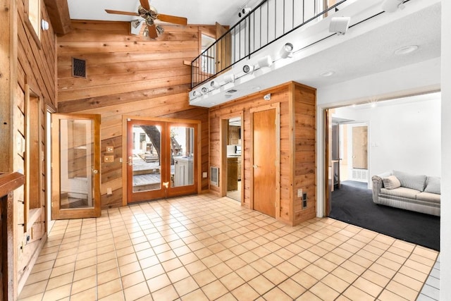 121 Scott St, San Marcos, TX 78666 - interior space featuring visible vents, a ceiling fan, wooden walls, a high ceiling, and light tile patterned floors