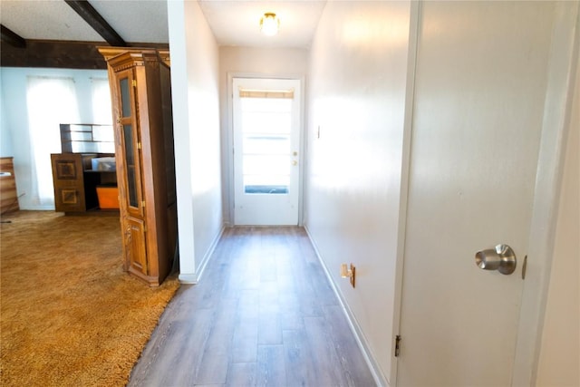 corridor with beamed ceiling, baseboards, and wood finished floors