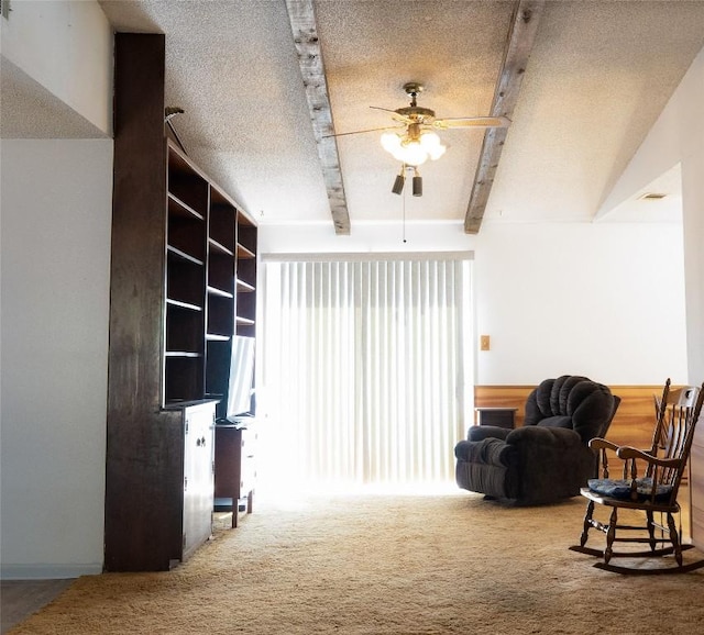 living area featuring beam ceiling, a textured ceiling, ceiling fan, and carpet flooring