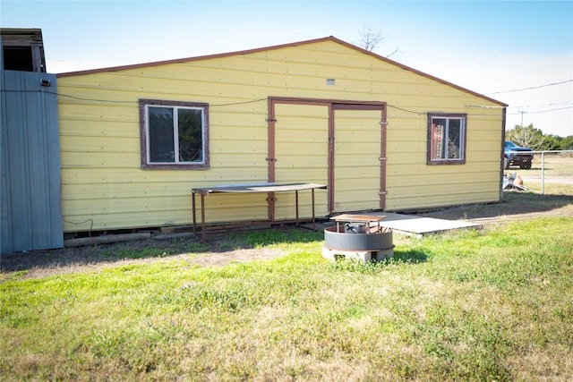 rear view of house with a lawn and fence