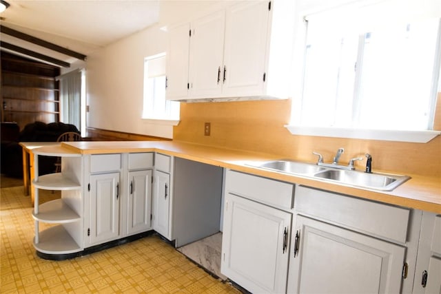 kitchen with open shelves, light countertops, decorative backsplash, white cabinets, and a sink