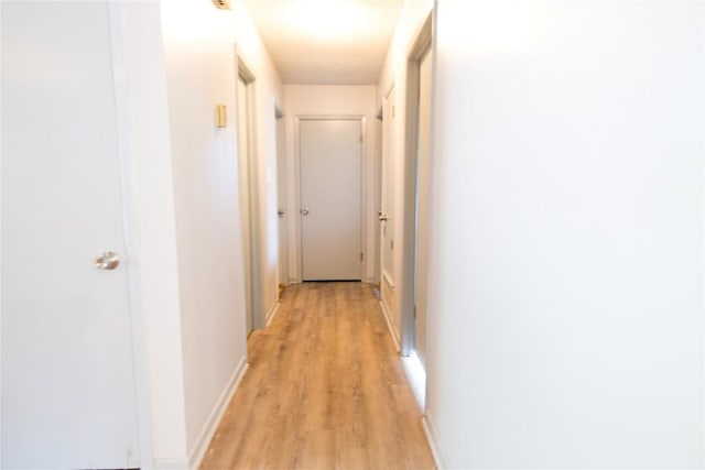 corridor featuring light wood-style floors and baseboards