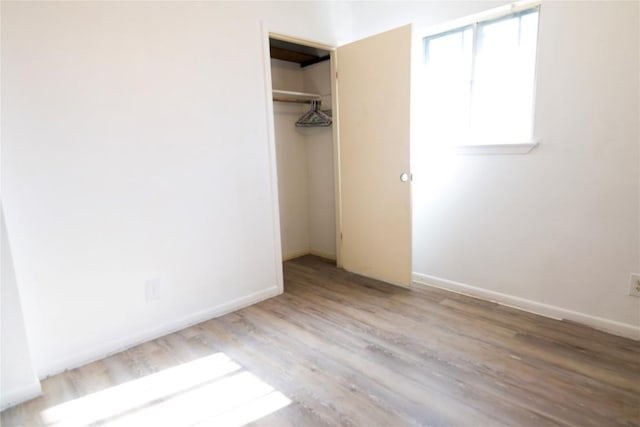 unfurnished bedroom with a closet, baseboards, and wood finished floors