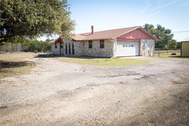 ranch-style house featuring aphalt driveway, a garage, fence, and stone siding