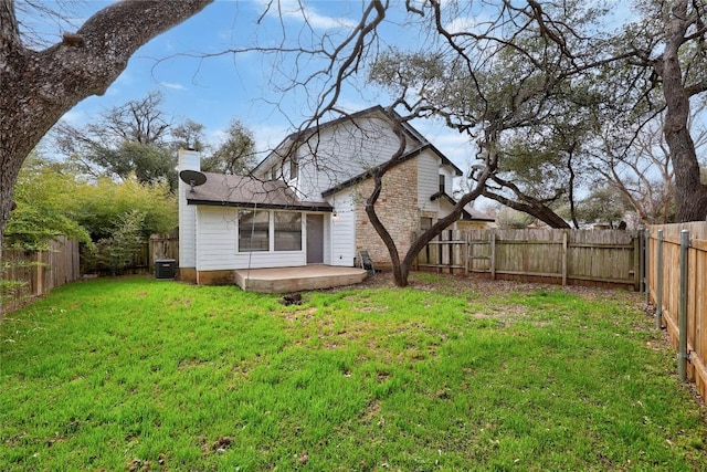 back of house with central AC unit, a yard, a fenced backyard, a chimney, and a patio area