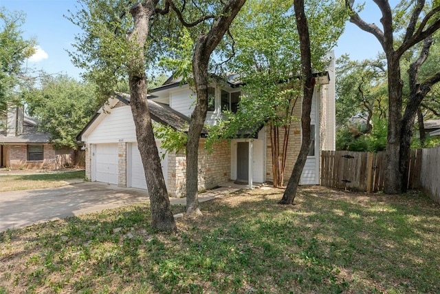 view of front of home featuring a front yard, fence, concrete driveway, a garage, and stone siding