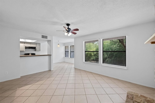 unfurnished living room with visible vents, a ceiling fan, a textured ceiling, light tile patterned flooring, and baseboards