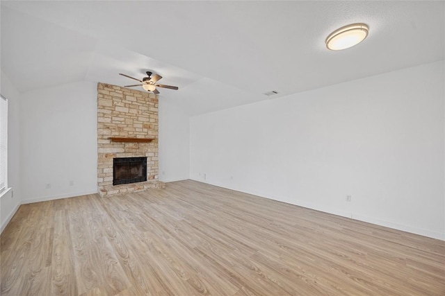 unfurnished living room with visible vents, a ceiling fan, wood finished floors, a fireplace, and vaulted ceiling