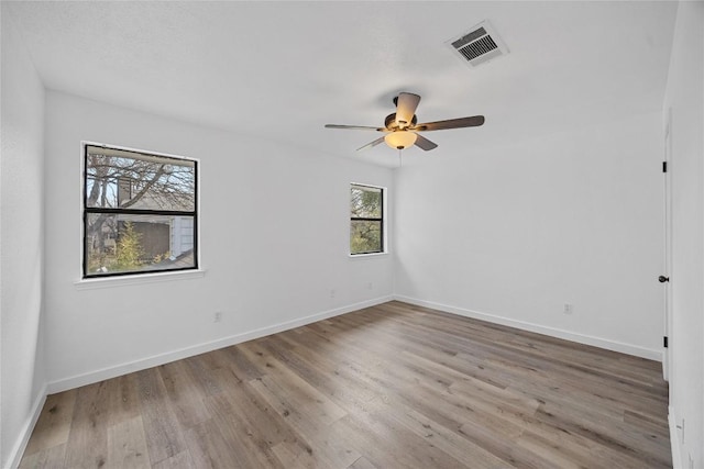 empty room featuring visible vents, ceiling fan, baseboards, and wood finished floors