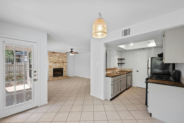 kitchen featuring dark countertops, light tile patterned floors, dishwasher, and freestanding refrigerator