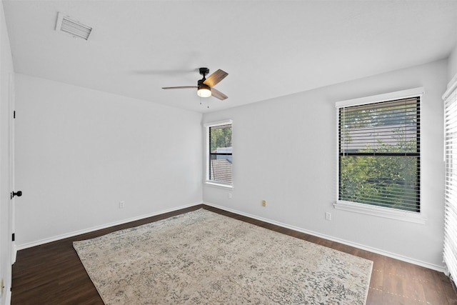 unfurnished room featuring ceiling fan, visible vents, baseboards, and dark wood finished floors