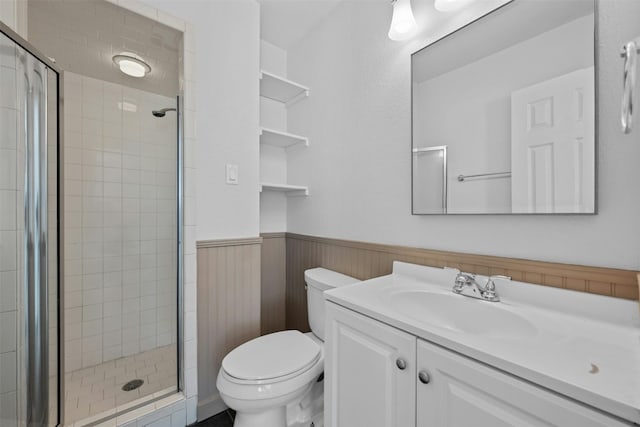 full bath with wainscoting, vanity, toilet, and a shower stall