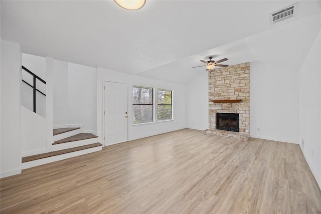 unfurnished living room with light wood-type flooring, visible vents, stairway, a fireplace, and lofted ceiling