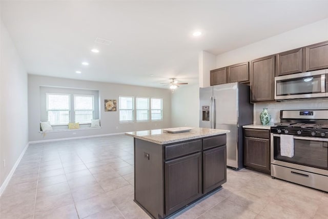 kitchen featuring a kitchen island, tasteful backsplash, dark brown cabinetry, appliances with stainless steel finishes, and baseboards