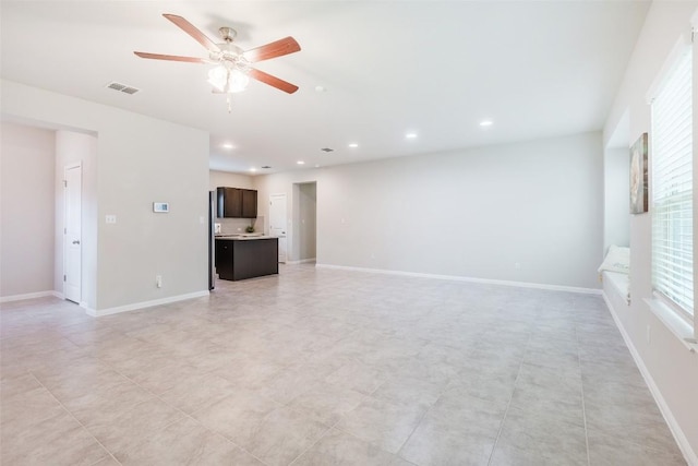 unfurnished living room featuring visible vents, baseboards, and a ceiling fan