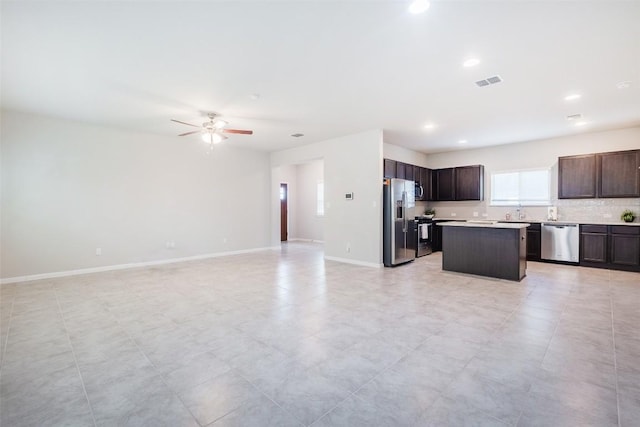 kitchen featuring open floor plan, appliances with stainless steel finishes, a center island, and baseboards