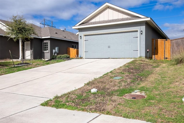 view of front of property with board and batten siding, a garage, and fence