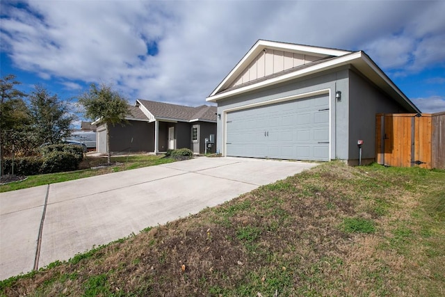 single story home featuring board and batten siding, concrete driveway, an attached garage, and a front yard